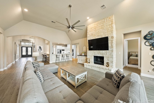 living area with visible vents, arched walkways, and dark wood-type flooring