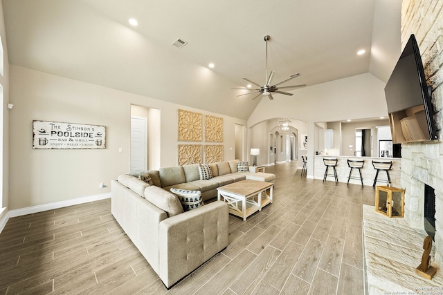 living area featuring high vaulted ceiling, ceiling fan, visible vents, and wood finish floors