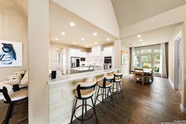 kitchen featuring light countertops, appliances with stainless steel finishes, white cabinetry, a peninsula, and a kitchen bar