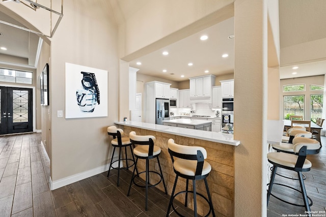 kitchen with light countertops, appliances with stainless steel finishes, white cabinetry, a peninsula, and a kitchen breakfast bar