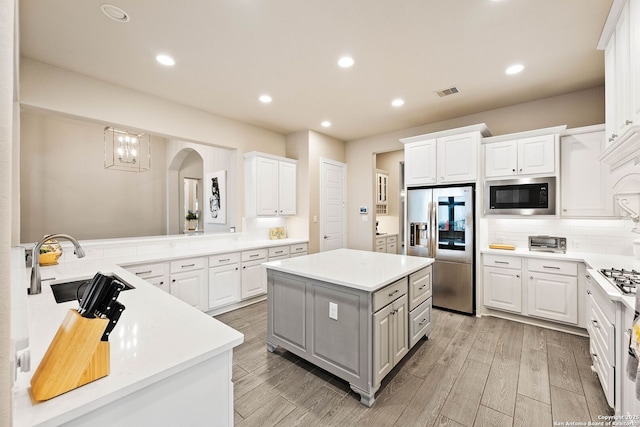 kitchen featuring appliances with stainless steel finishes, light countertops, white cabinetry, and a kitchen island