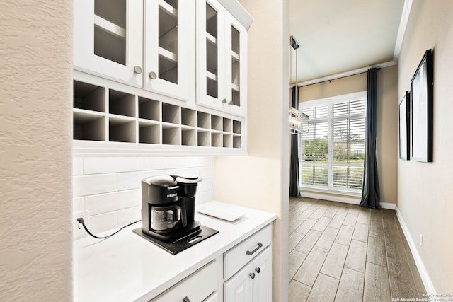 kitchen with white cabinets, glass insert cabinets, decorative light fixtures, light countertops, and backsplash