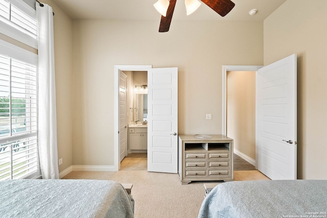 bedroom featuring baseboards, connected bathroom, a ceiling fan, and light colored carpet