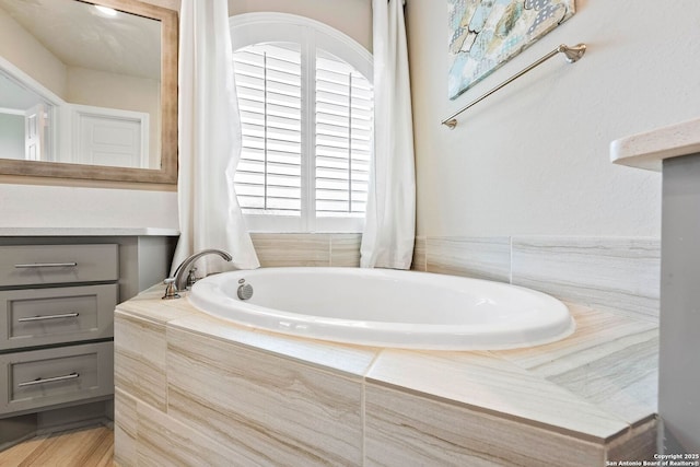 bathroom with a garden tub and vanity