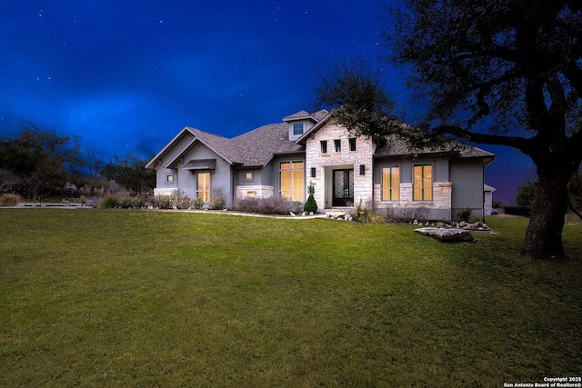 view of front of property featuring stone siding and a lawn