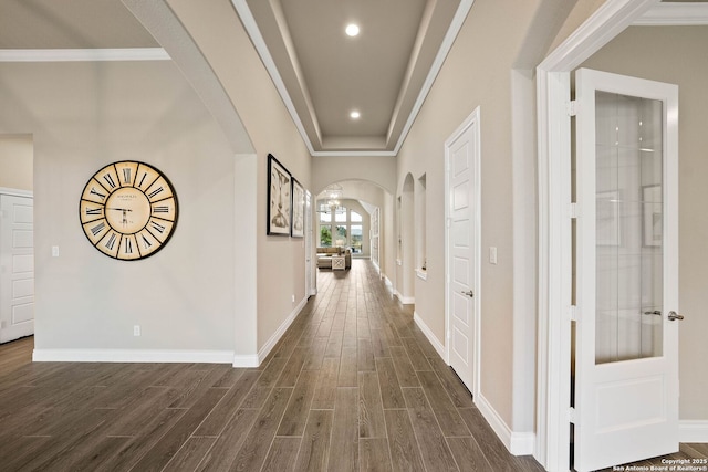 corridor featuring baseboards, arched walkways, dark wood finished floors, crown molding, and recessed lighting