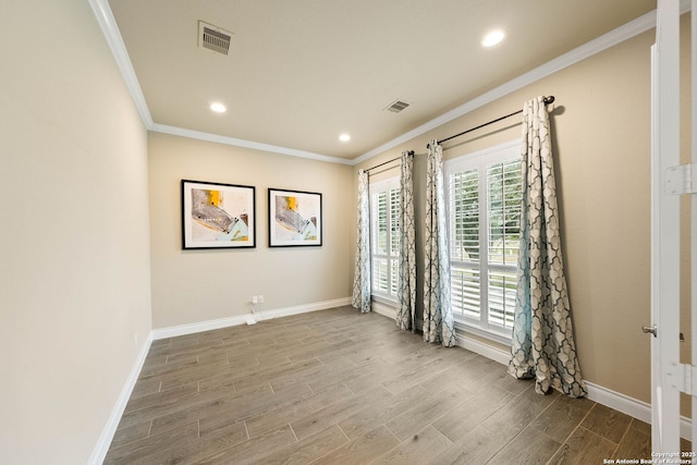 empty room featuring baseboards, wood finished floors, visible vents, and crown molding