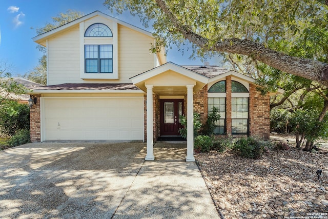 traditional home featuring an attached garage, concrete driveway, and brick siding