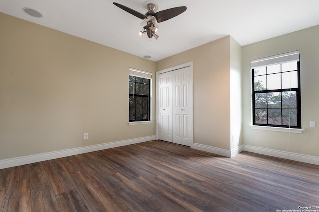 unfurnished bedroom featuring a ceiling fan, a closet, dark wood finished floors, and baseboards