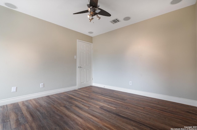 unfurnished room featuring dark wood-style floors, a ceiling fan, visible vents, and baseboards