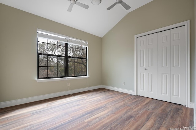 unfurnished bedroom with a closet, ceiling fan, vaulted ceiling, wood finished floors, and baseboards