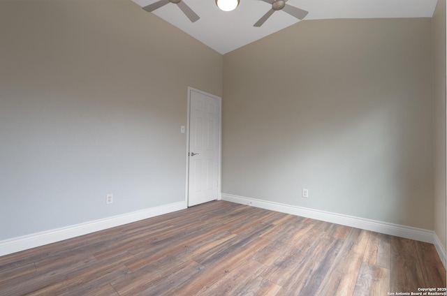 empty room featuring vaulted ceiling, dark wood-type flooring, a ceiling fan, and baseboards