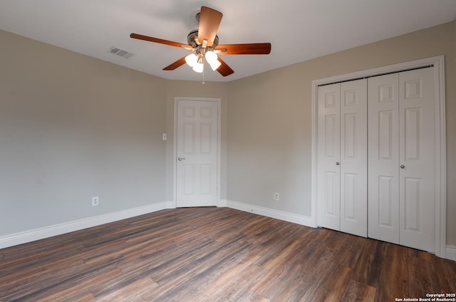 unfurnished bedroom with baseboards, visible vents, ceiling fan, dark wood-type flooring, and a closet