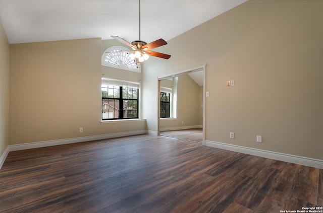 spare room with dark wood-type flooring, ceiling fan, high vaulted ceiling, and baseboards