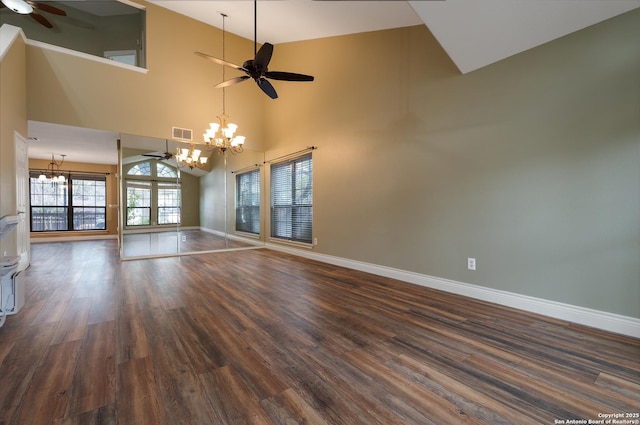 unfurnished living room featuring ceiling fan with notable chandelier, a towering ceiling, visible vents, baseboards, and dark wood finished floors