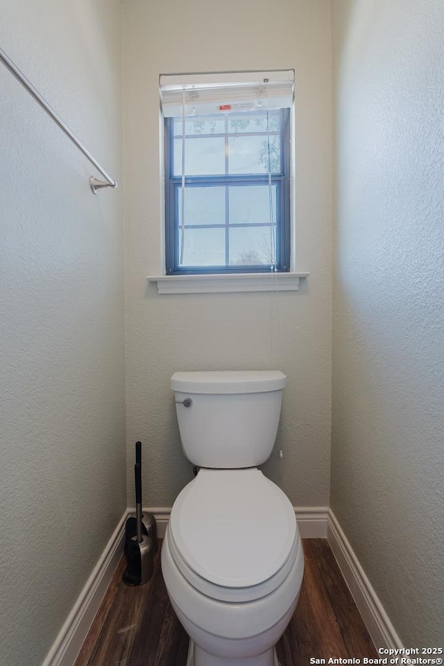 bathroom featuring baseboards, a textured wall, toilet, and wood finished floors