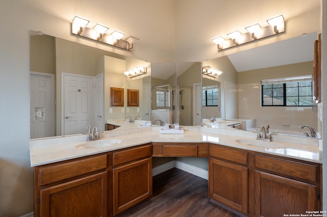 bathroom with lofted ceiling, a garden tub, vanity, and wood finished floors