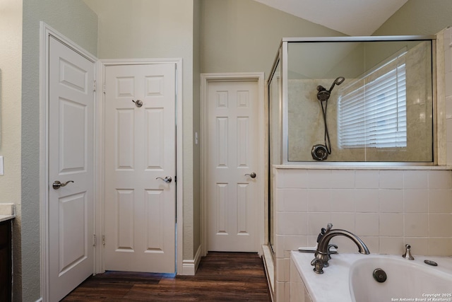 full bath with vaulted ceiling, wood finished floors, a shower stall, and a bath