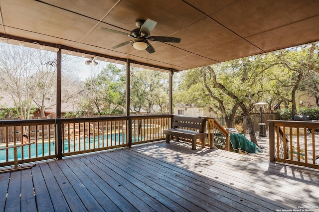 wooden deck featuring ceiling fan, fence, and a fenced in pool