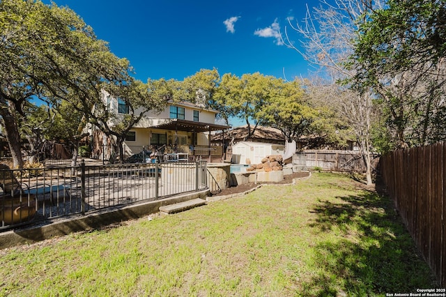 view of yard with a storage shed, a fenced backyard, a patio, and an outbuilding