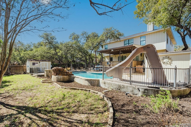 view of pool featuring an outbuilding, a water slide, fence, a fenced in pool, and a storage unit