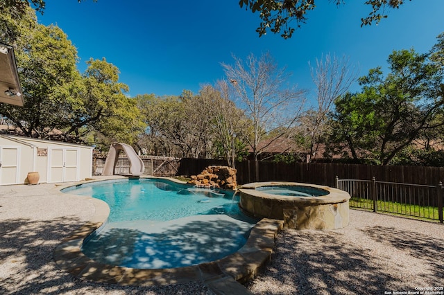 view of pool featuring a fenced backyard, a storage unit, a water slide, and an outbuilding