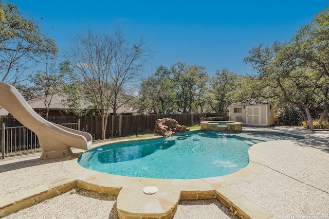 view of pool with a storage unit, a pool with connected hot tub, a water slide, a fenced backyard, and an outdoor structure