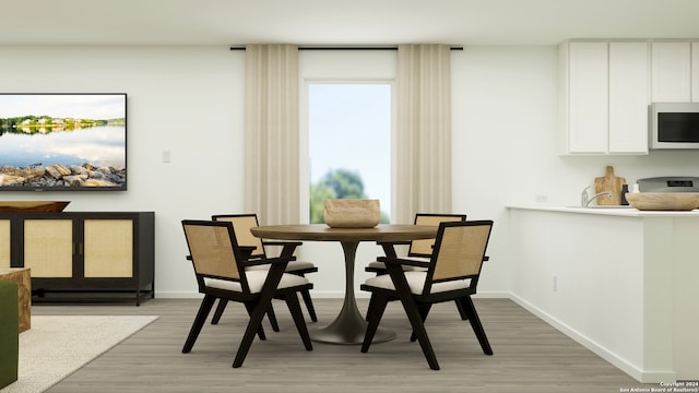 dining space with baseboards and light wood-style floors