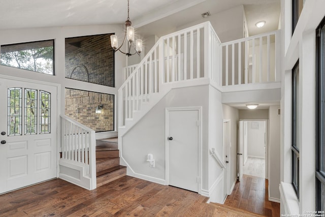 foyer with visible vents, a chandelier, wood finished floors, stairs, and high vaulted ceiling