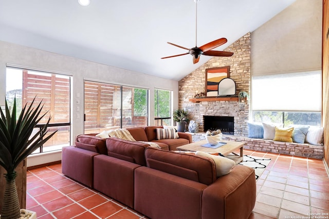 tiled living room featuring high vaulted ceiling, a stone fireplace, and a ceiling fan