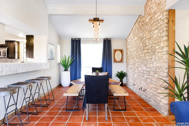 tiled dining space with vaulted ceiling with beams and baseboards