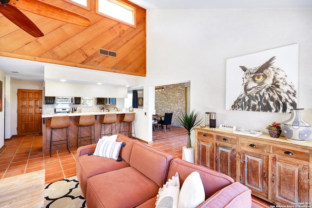 living room featuring light tile patterned floors, visible vents, and high vaulted ceiling