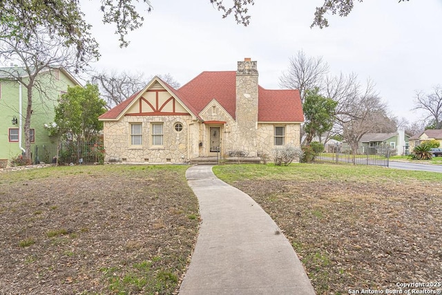 english style home featuring crawl space, stone siding, a chimney, and fence