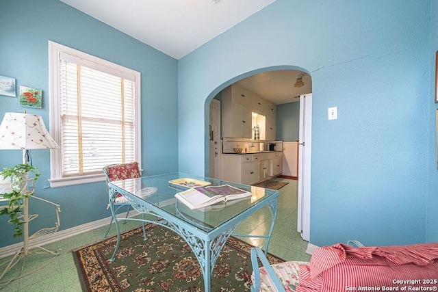 dining area with arched walkways, baseboards, and tile patterned floors