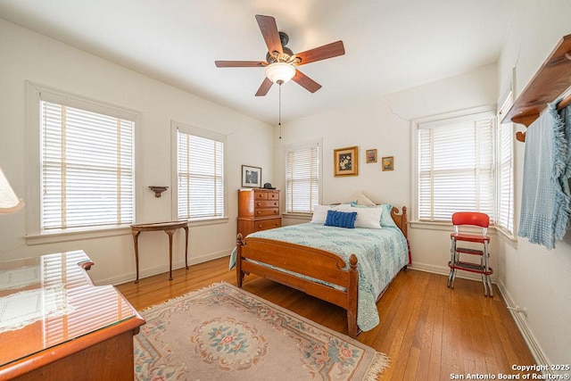 bedroom featuring light wood-style flooring, multiple windows, baseboards, and ceiling fan