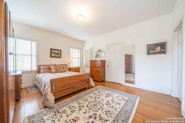 bedroom with light wood-type flooring, multiple windows, and baseboards