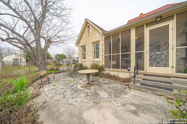 view of patio / terrace with entry steps, a sunroom, and fence