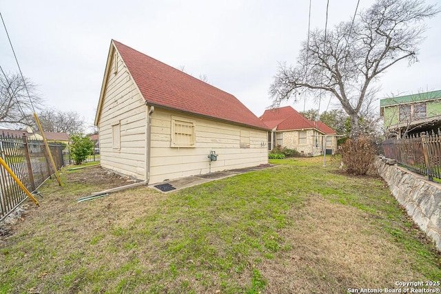 exterior space featuring roof with shingles, a lawn, and a fenced backyard