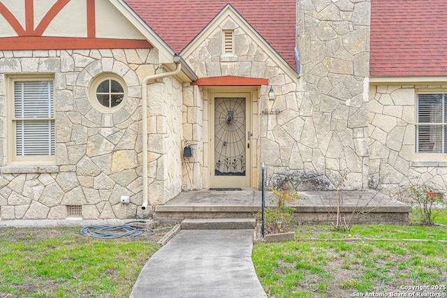 view of exterior entry with a shingled roof and stone siding