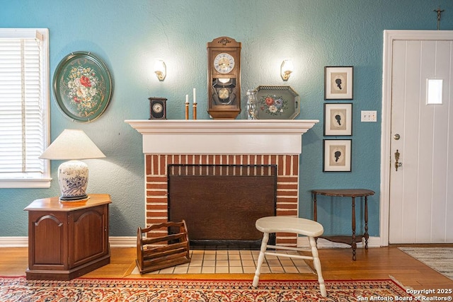 interior space with a brick fireplace, baseboards, and wood finished floors