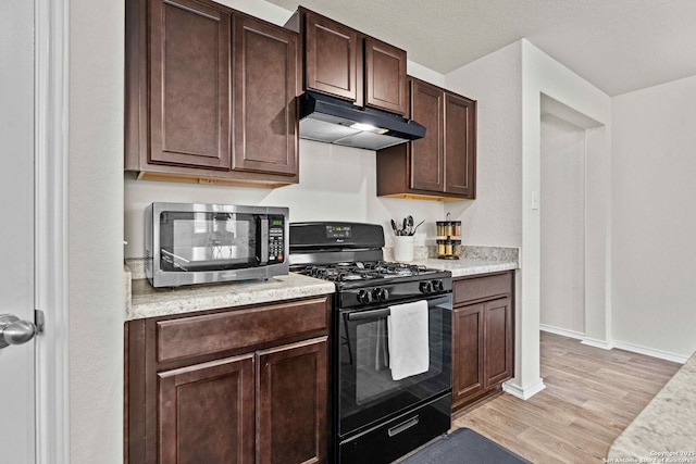 kitchen featuring under cabinet range hood, light countertops, and gas stove