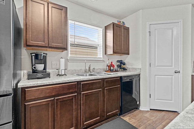 kitchen featuring light countertops, light wood-style floors, freestanding refrigerator, a sink, and dishwasher