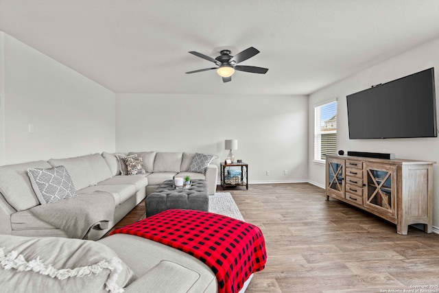 living area featuring ceiling fan, baseboards, and wood finished floors