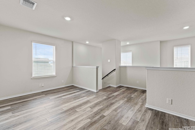 unfurnished room featuring light wood-type flooring, a healthy amount of sunlight, visible vents, and recessed lighting