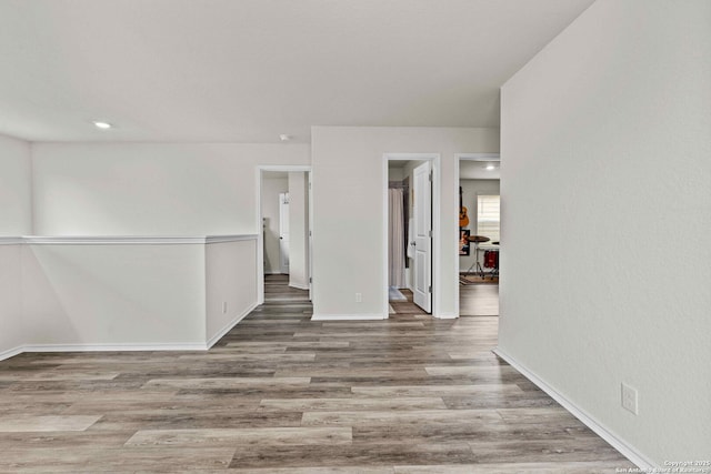 spare room featuring recessed lighting, wood finished floors, and baseboards