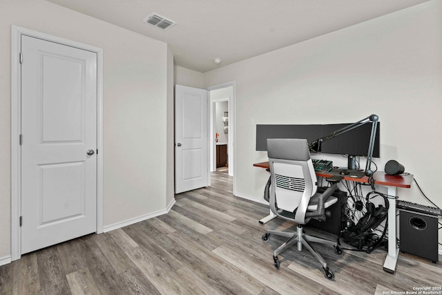 home office featuring visible vents, light wood-style flooring, and baseboards