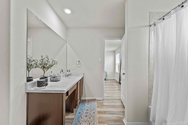 full bath with a shower with shower curtain, vanity, baseboards, and wood finished floors