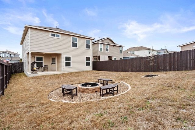 rear view of house featuring a fire pit, a patio, a lawn, and a fenced backyard