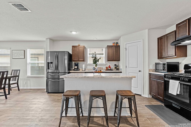 kitchen featuring appliances with stainless steel finishes, a center island, visible vents, and a breakfast bar area