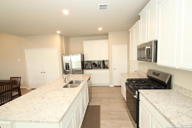 kitchen with visible vents, appliances with stainless steel finishes, white cabinetry, a sink, and an island with sink